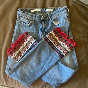 Blue jeans with embroidered bottoms.